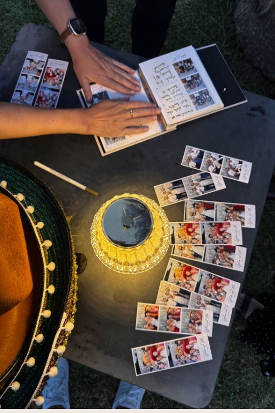 Álbum de firmas del fotomatón llenándose con tiras de fotos, junto a un sombrero español — boda en Villa Golf, Sitges