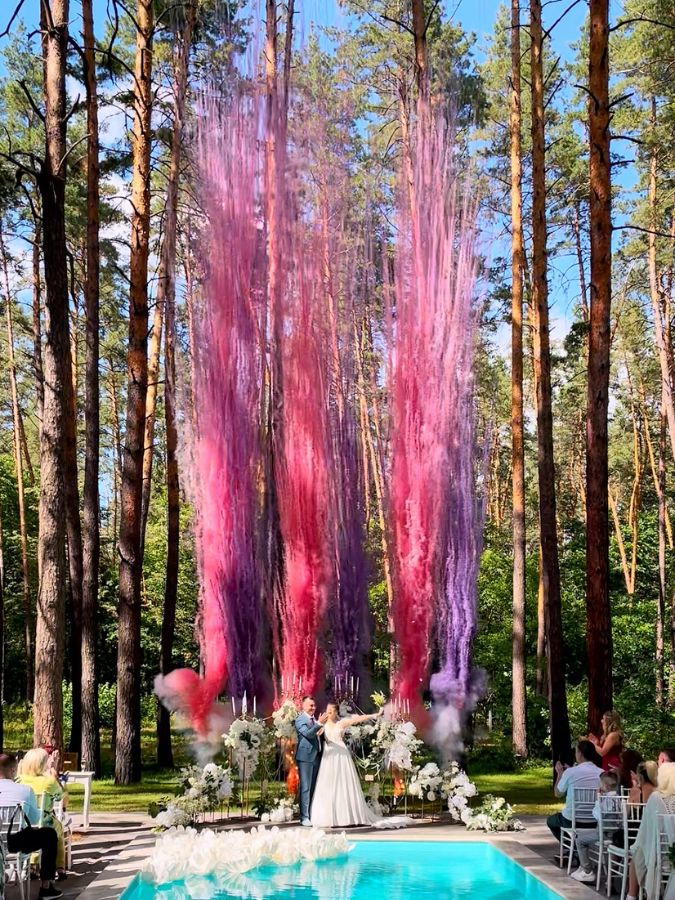 Columnas de humo rosa sobre piscina en boda en el bosque