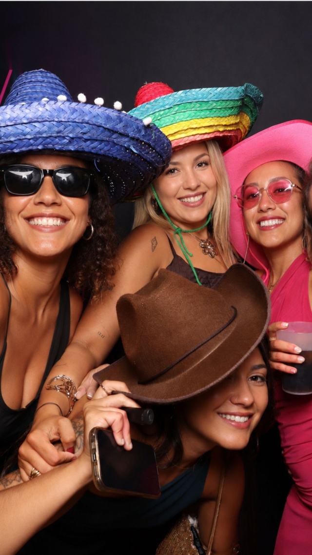 Cuatro amigas con sombreros de colores y gafas de sol riendo en el fotomatón — fotomatón para bodas y eventos