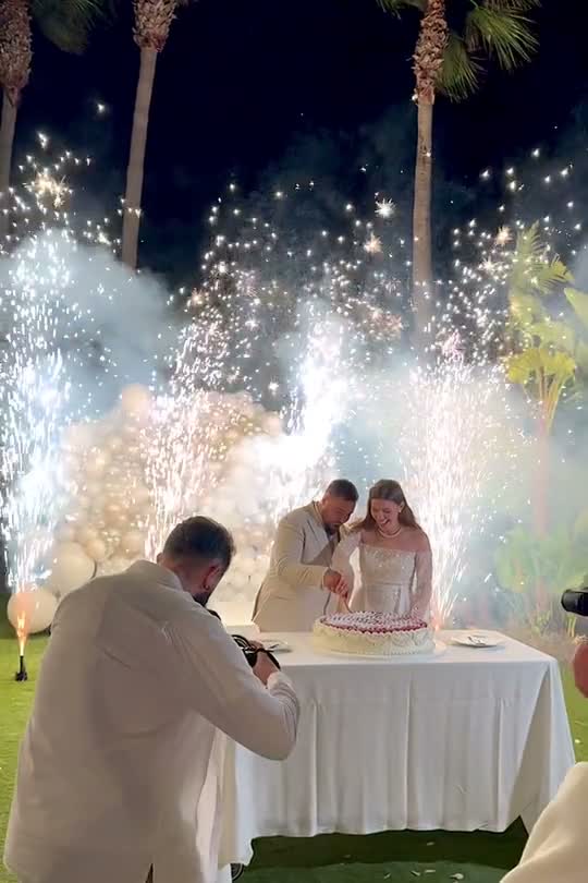 Corte de tarta con chispas frías entre palmeras