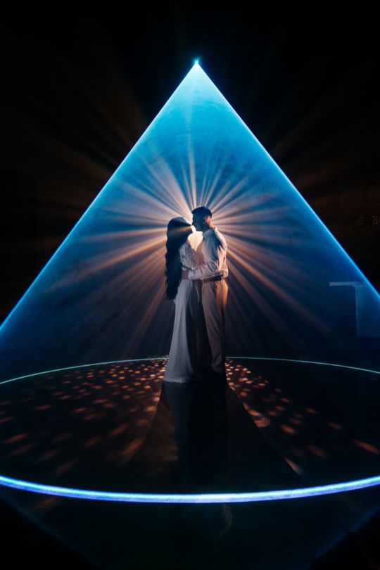 Primer baile de novios bajo cono de luz láser azul — efecto Cenicienta boda Barcelona